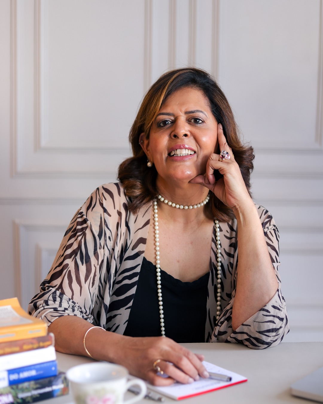 Silvia Mara sorrindo, sentada à mesa de trabalho